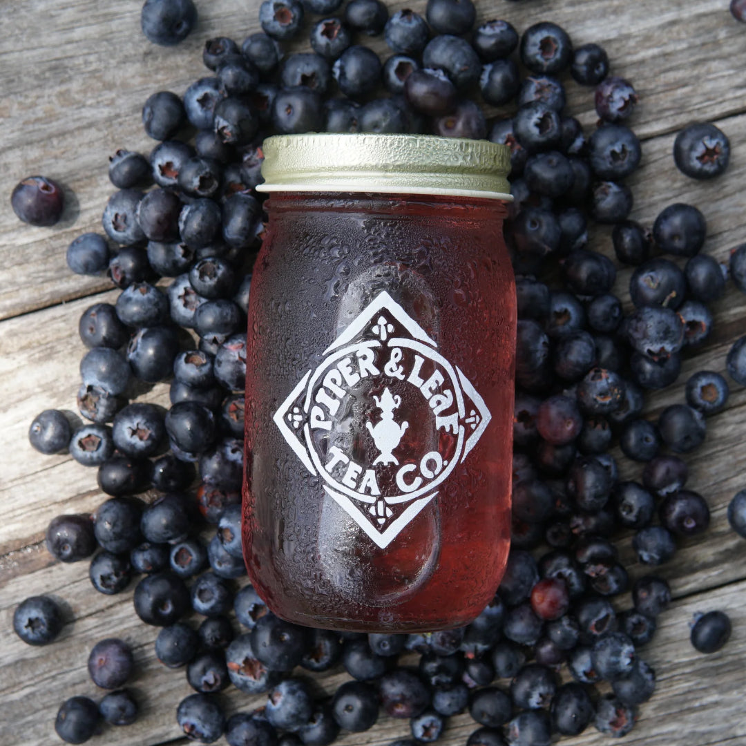 Jar of tea from Piper & Leaf Tea Co. surrounded by blueberries on a wooden surface